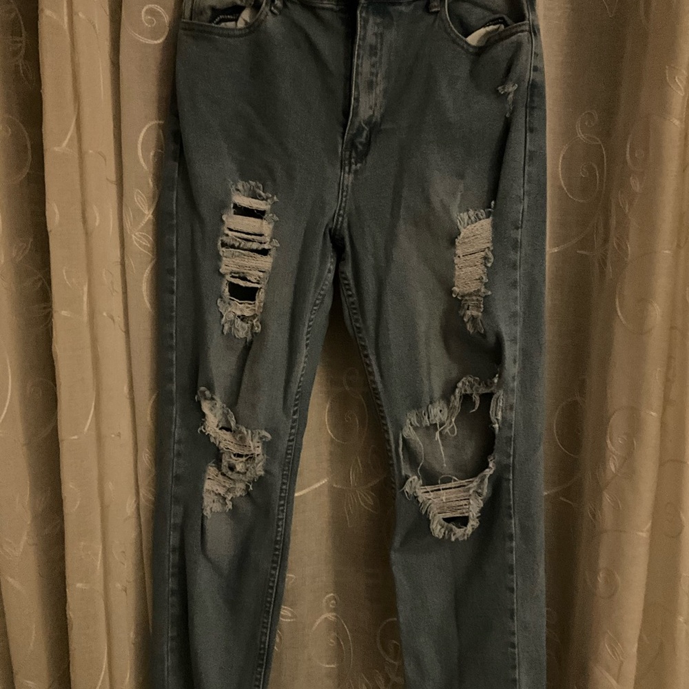 A pair of light-washed blue jeans with rips above the knee.